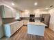 Well-lit kitchen with stainless steel appliances, white cabinets, an island, and wood-look flooring at 5629 Boulder Blvd, Sarasota, FL 34233