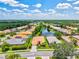 Aerial view of a vibrant community with mature trees, a serene pond, and well-maintained homes with colorful roofs at 6216 Donnington Ct, Sarasota, FL 34238
