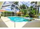 Backyard with screened pool, jacuzzi, patio area and view of mature landscaping and blue skies at 6216 Donnington Ct, Sarasota, FL 34238