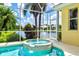 Screened-in pool and hot tub overlooking a serene lake, framed by lush tropical foliage at 6216 Donnington Ct, Sarasota, FL 34238