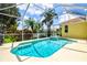 Backyard with screened pool, jacuzzi, patio area and view of mature landscaping and blue skies at 6216 Donnington Ct, Sarasota, FL 34238