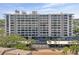 Exterior view of a beachfront condo with garage parking and palm tree lined entrance at 6415 Midnight Pass Rd # 502, Sarasota, FL 34242