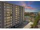 Well-lit modern condo building boasting multiple balconies, a pool, and convenient parking, with a colorful sunset backdrop at 6415 Midnight Pass Rd # 502, Sarasota, FL 34242