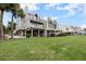 Multi-story home featuring balconies, large windows, and green lawn with palm trees on waterfront property at 65 Tidy Island Blvd, Bradenton, FL 34210