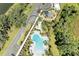 Overhead drone view of a kidney-shaped pool and playground, surrounded by lush landscaping and parking area at 7160 Amelia River Dr, Parrish, FL 34219