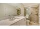 Bathroom featuring speckled vanity countertop, large mirror, and tiled shower with grab bars for safety and accessibility at 8239 Cypress Hollow Dr, Sarasota, FL 34238