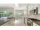 Bright kitchen features white cabinets, stainless steel appliances, stone countertops, and a sunlit breakfast nook at 8239 Cypress Hollow Dr, Sarasota, FL 34238