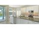 Bright kitchen features white cabinets, stone countertops, and stainless steel appliances overlooking the pool area at 8239 Cypress Hollow Dr, Sarasota, FL 34238