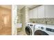 Laundry room with hummingbird-themed wallpaper, utility sink, and modern washer and dryer units at 8239 Cypress Hollow Dr, Sarasota, FL 34238