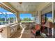 Outdoor kitchen with stainless steel grill, bar seating, pond view, and an adjacent comfortable seating area at 8315 Eagle Xing, Sarasota, FL 34241