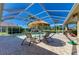 The screened in pool area features comfortable lounge chairs and an umbrella for sun protection at 8315 Eagle Xing, Sarasota, FL 34241
