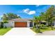 Charming single-story home with a wood garage door, manicured landscaping, and a well-maintained lawn at 891 Faulkwood Ct, Sarasota, FL 34232