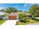 Charming single-story home featuring a wood-paneled garage door, manicured lawn, and lush landscaping at 891 Faulkwood Ct, Sarasota, FL 34232