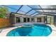 Relax in this covered pool area with spa and backyard views of the landscaped yard and home at 891 Faulkwood Ct, Sarasota, FL 34232