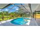 Screened pool area featuring a relaxing spa and serene backyard views of lush greenery and water at 891 Faulkwood Ct, Sarasota, FL 34232