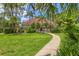 Beautiful fenced backyard with manicured lawn, tropical trees, and a concrete walkway, leading to a view of a house at 924 La Costa Cir # 4, Sarasota, FL 34237