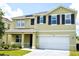 Two-story home featuring a two-car garage, dark shutters, and solar panels on the roof at 10019 Geese Trail Cir, Sun City Center, FL 33573