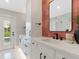 Bright bathroom with white vanity, black hardware, decorative mirror, and a door with natural light at 1031 Contento St, Sarasota, FL 34242