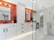 Modern bathroom with a glass walk-in shower, bright white vanity, black hardware, and orange accent wall tiles at 1031 Contento St, Sarasota, FL 34242