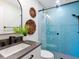 Well-lit bathroom features a modern sink, decorative woven baskets, and a blue tiled glass enclosed shower at 1031 Contento St, Sarasota, FL 34242