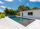 A beautiful backyard pool with a spa and sleek modern tiling is surrounded by lush green landscaping at 1031 Contento St, Sarasota, FL 34242