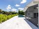 The blue in-ground pool overlooks a green hedge under a blue sky, connected by stone patio at 1031 Contento St, Sarasota, FL 34242