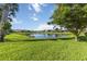 View of the lush, green lawn and lake in the backyard on a sunny day at 11221 Sandhill Preserve Dr, Sarasota, FL 34238