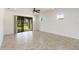 Bright, empty living room with neutral color scheme, tile flooring, and a sliding glass door leading to the outside at 11221 Sandhill Preserve Dr, Sarasota, FL 34238