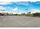 Well-maintained tennis court with lighting, surrounded by lush landscaping and clear skies at 11221 Sandhill Preserve Dr, Sarasota, FL 34238
