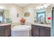 Bright bathroom featuring a large tub, dual vanities with granite countertops, and decorative wall art at 12398 Keyridge Loop, Largo, FL 33778