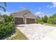 Charming single-story home featuring a three-car garage, mature landscaping, and a brick-paved driveway at 12398 Keyridge Loop, Largo, FL 33778