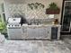 Outdoor kitchen with stainless steel grill, sink, refrigerator, and beautiful stone and mosaic tile backsplash at 12398 Keyridge Loop, Largo, FL 33778