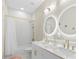 Bathroom featuring double vanity, marble countertops, dual round mirrors, and a tub with a shower at 15815 Tradewind Ter, Bradenton, FL 34211