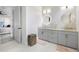 Bathroom with double vanity, round mirrors with halo lighting, and grey cabinets on tile flooring at 15815 Tradewind Ter, Bradenton, FL 34211