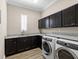 Laundry room featuring granite counters, dark cabinetry, and modern washer/dryer at 16628 Berwick Ter, Lakewood Ranch, FL 34202