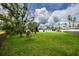 Spacious backyard features lush green grass, mature trees, and ample space for outdoor activities at 211 22Nd Street Ne Ct, Bradenton, FL 34208