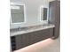 Bright bathroom featuring double vanity, gray cabinets, marble countertops, and illuminated mirrors at 2110 Michele Dr, Sarasota, FL 34231