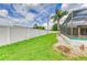 Expansive backyard with a vinyl fence, lush grass, and a screened-in pool area, offering privacy and outdoor enjoyment at 23136 Langdon Ave, Port Charlotte, FL 33954