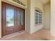Close-up of the front door with glass detailing, a tiled entryway, and an exterior window at 23136 Langdon Ave, Port Charlotte, FL 33954