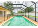 Inviting screened-in pool and spa surrounded by lush landscaping and brick patio at 23136 Langdon Ave, Port Charlotte, FL 33954