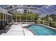 Screened-in pool with brick trim, complemented by tropical landscaping, offering a private oasis at 3167 Pinetree St, Port Charlotte, FL 33952