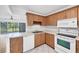 Bright kitchen features wood cabinets, white appliances, and tile flooring with views of the lanai and lush greenery at 3640 Ironwood Cir # 302N, Bradenton, FL 34209