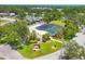 Aerial view of community pool with screened enclosure, lush landscaping, and shuffleboard courts at 3640 Ironwood Cir # 302N, Bradenton, FL 34209