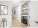 Hallway with light hardwood floors, an ornate mirror, and built in shelves with a shoe rack at 3673 Fescue Ln, Sarasota, FL 34232