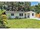 View of a freshly painted single-story home featuring a well-maintained lawn and lovely, mature shade trees at 4041 Linwood St, Sarasota, FL 34232