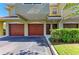 Close up view of townhome garages with brick-red doors and well manicured shrubs at 5001 Baraldi Cir # 22-202, Sarasota, FL 34235