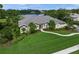 A single-story home with lush landscaping, a well-manicured lawn, and views of a serene lake at 5012 Cherry Laurel Way, Sarasota, FL 34241
