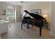 Well-lit living room features a grand piano, desk, and large window with shutters at 5012 Cherry Laurel Way, Sarasota, FL 34241