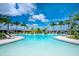 Large community pool with clear blue water surrounded by lounge chairs, palm trees, and well-maintained landscaping at 5533 Long Shore Loop, Sarasota, FL 34238