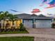 Charming single-story home with a paver driveway, two-car garage, tropical landscaping, and a beautiful blue sky at 5533 Long Shore Loop, Sarasota, FL 34238